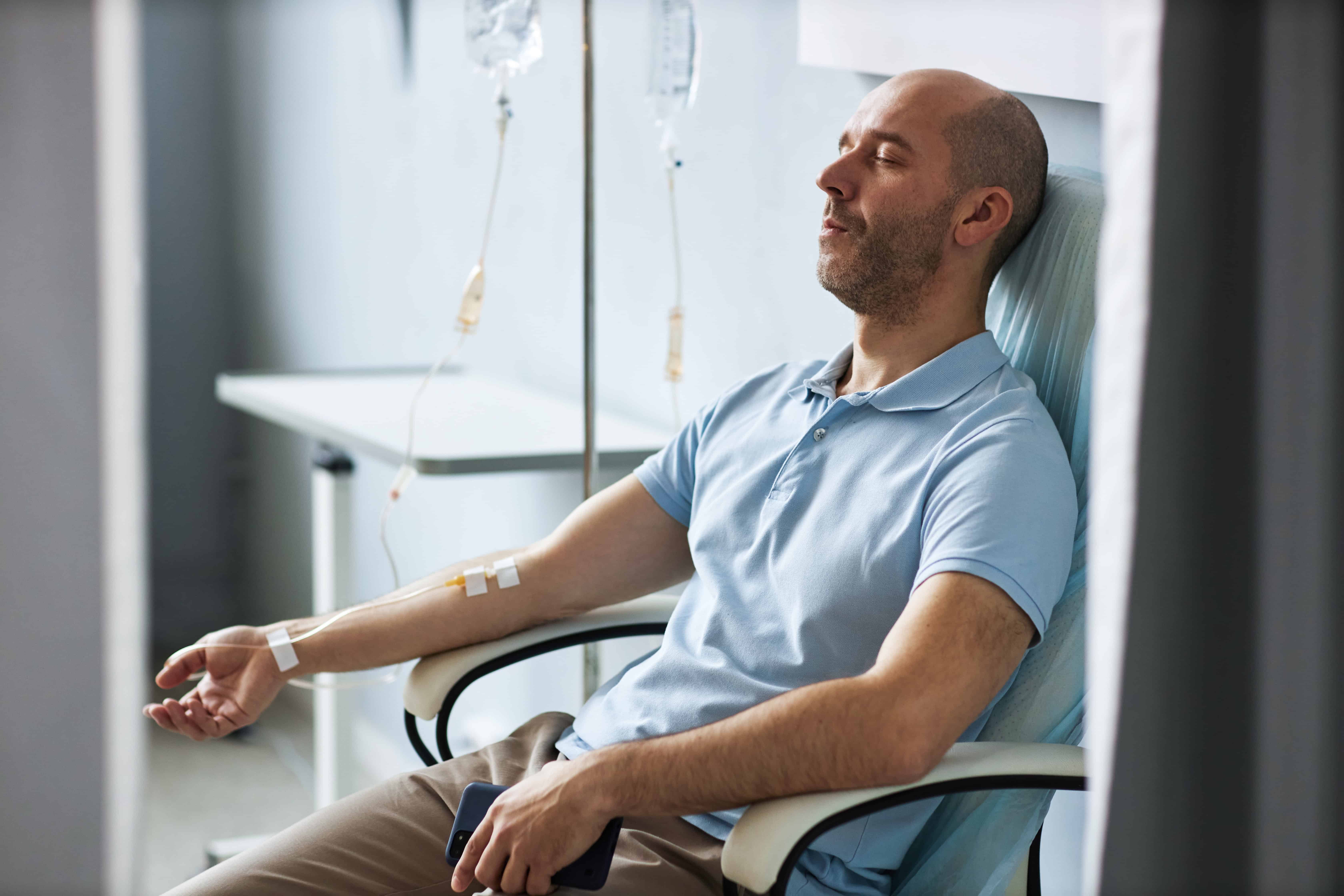 Man sitting in chair with IV drip during treatment session and relaxing