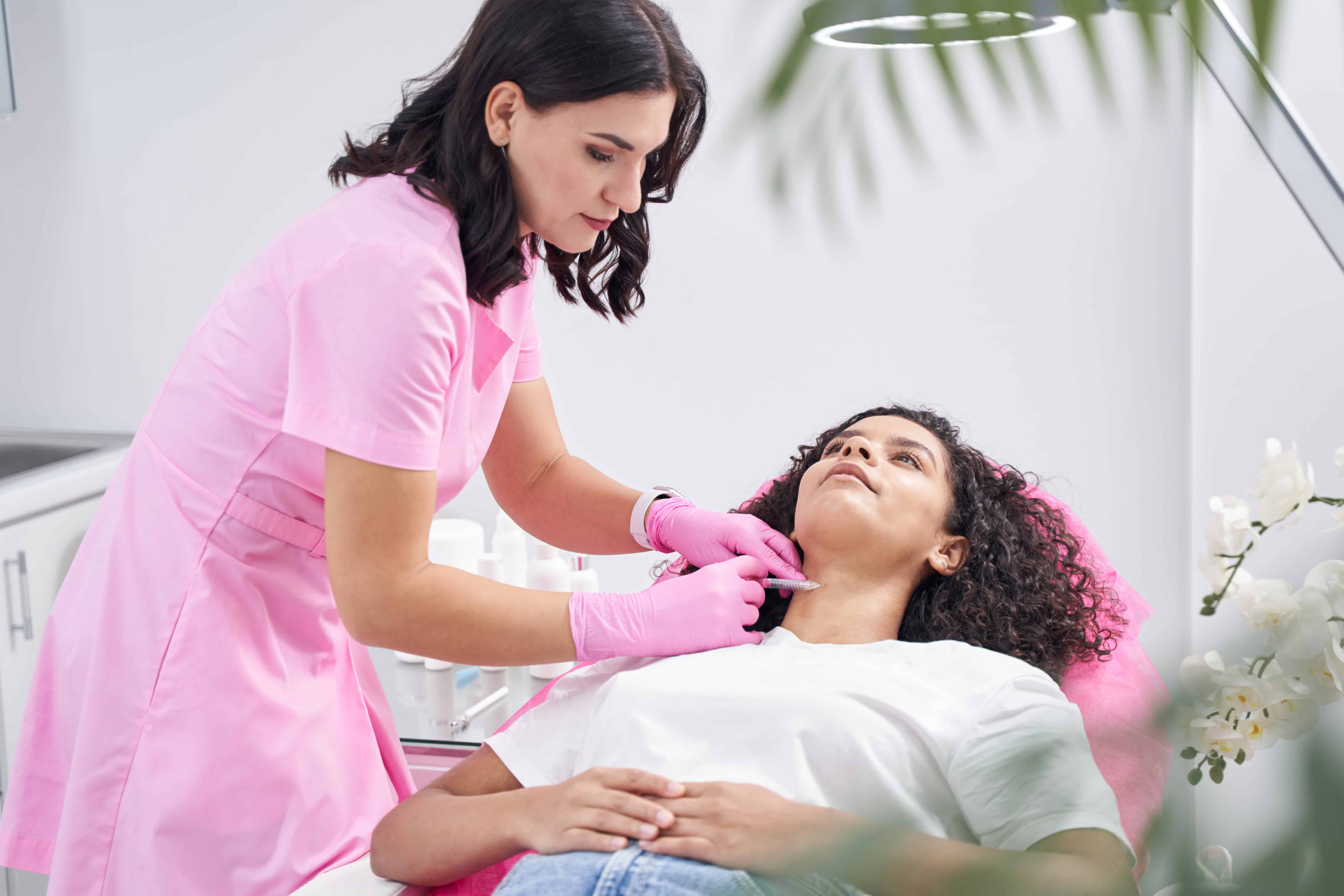 Woman doctor injecting into the neck of a young patient